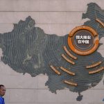 
              A custodian stands near a map showing Evergrande development projects in China on a wall in an Evergrande city plaza in Beijing, Tuesday, Sept. 21, 2021. Global investors are watching nervously as the Evergrande Group, one of China's biggest real estate developers, struggles to avoid defaulting on tens of billions of dollars of debt, fueling fears of possible wider shock waves for the Chinese financial system. (AP Photo/Andy Wong)
            