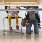 
              A young mother with two children kneels behind the voting booth at a polling station for the German Parliament election in Berlin, Germany, Sunday, Sept. 26, 2021. On Sept. 26, 2021 about 60.4 million people in the nation of 83 million are eligible to elect the new Bundestag, or lower house of parliament, which will elect the next head of government. (Bernd von Jutrczenka/dpa via AP)
            
