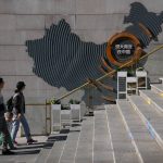 
              A family walks by a map showing Evergrande development projects in China at an Evergrande city plaza in Beijing, Tuesday, Sept. 21, 2021. Global investors are watching nervously as the Evergrande Group, one of China's biggest real estate developers, struggles to avoid defaulting on tens of billions of dollars of debt, fueling fears of possible wider shock waves for the Chinese financial system. (AP Photo/Andy Wong)
            