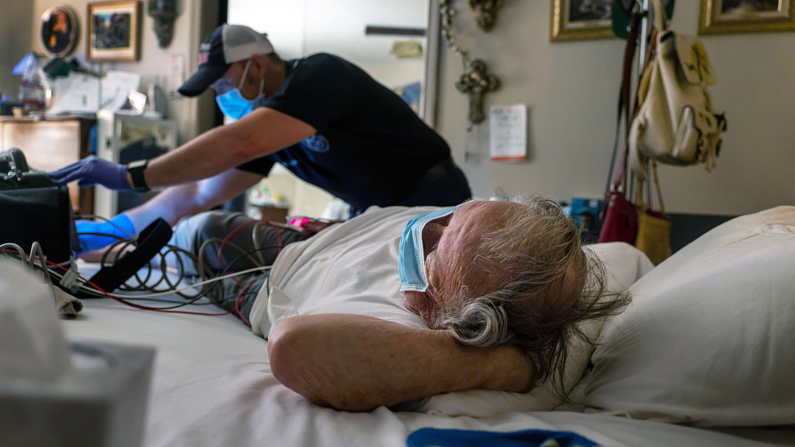 A medic checks the vital signs of a COVID-positive man, 83, before transporting him to a hospital o...