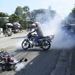 
              Motorcyclists unable to find gas for sale at a fuel station are repelled by police with tear gas outside the home of acting Prime Minister Ariel Henry where they drove to protest in Port-au-Prince, Haiti, Tuesday, Oct. 19, 2021, on the day of a strike against rising violence. (AP Photo/Matias Delacroix)
            