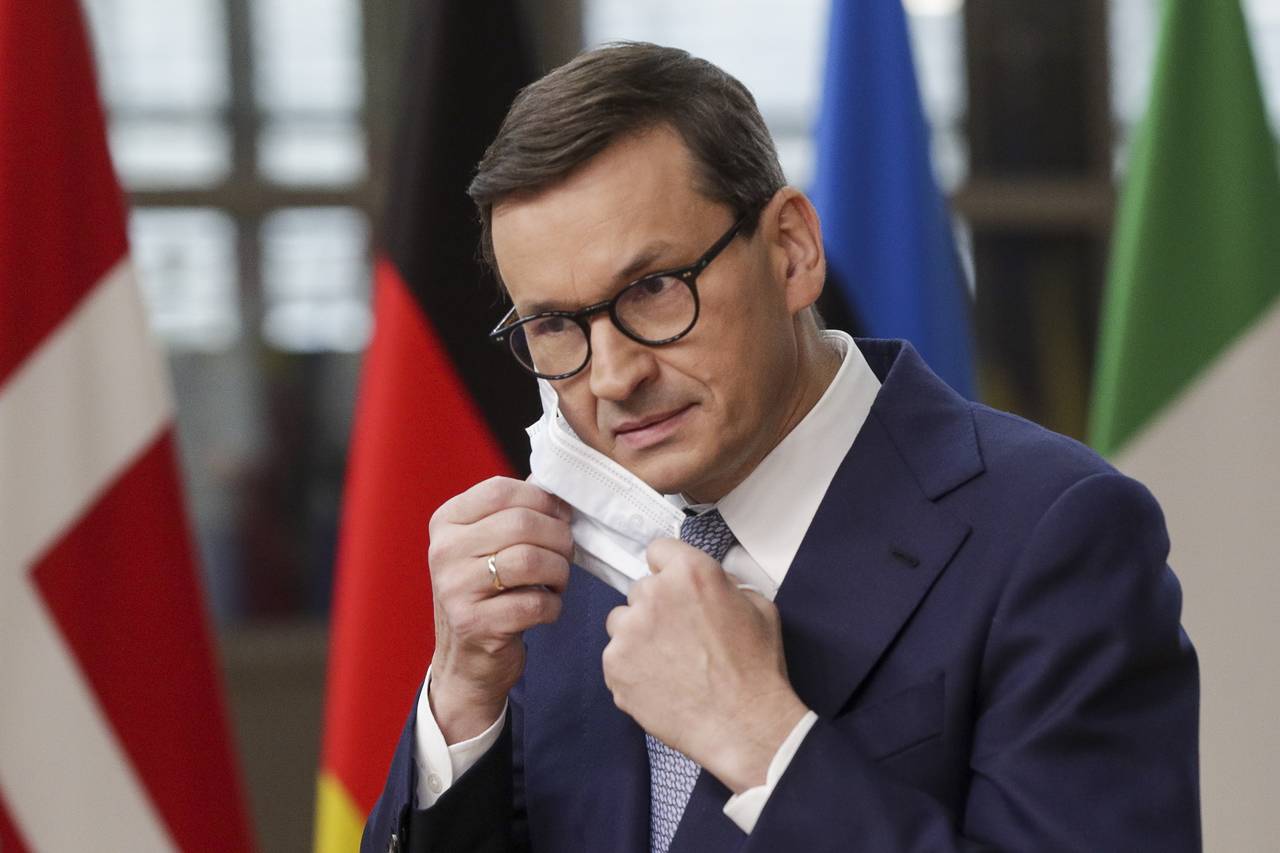 Poland's Prime Minister Mateusz Morawiecki removes his protective face masks as he arrives for an E...