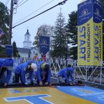 
              Volunteers put the finishing touches on the timing mat at the starting line of the 125th Boston Marathon, Monday, Oct. 11, 2021, in Hopkinton, Mass. (AP Photo/Mary Schwalm)
            