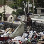 A man retrieves utensils among the trash in Port-au-Prince, Haiti, Monday, Oct. 18, 2021. Workers angry about the nation's lack of security went on strike in protest two days after 17 members of a U.S.-based missionary group were abducted by a violent gang. (AP Photo/Joseph Odelyn)