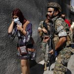 
              Lebanese army special forces soldiers protect teachers as they flee their school after deadly clashes erupted along a former 1975-90 civil war front-line between Muslim Shiite and Christian areas, at Ain el-Remaneh neighborhood, in Beirut, Lebanon, Thursday, Oct. 14, 2021. Armed clashes broke out in Beirut Thursday during the protest against the lead judge investigating last year's massive blast in the city's port, as tensions over the domestic probe boiled over. (AP Photo/Hussein Malla)
            