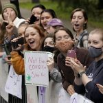 
              Women displays signs and cheer in front Wellesley College, in Wellesley, Mass., as a runner passes during the 125th Boston Marathon, Monday, Oct. 11, 2021. (AP Photo/Steven Senne)
            