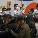 Service sector workers wearing face masks to help curb the spread of the coronavirus line up  during a mass COVID-19 testing in Beijing, Friday, Oct. 29, 2021, following a spike of the coronavirus in the capital and other provincials. (AP Photo/Andy Wong)