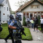 
              FILE - In this May 28, 2020, file photo, protesters and residents watch as police in riot gear walk down a residential street, in St. Paul, Minn. Reports of hateful and violent speech on Facebook poured in on the night of May 28 after President Donald Trump hit send on a social media post warning that looters who joined protests following Floyd's death last year would be shot, according to internal Facebook documents shared with The Associated Press. (AP Photo/John Minchillo, File)
            