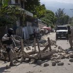 Police remove a roadblock set by protesters in Port-au-Prince, Haiti, Monday, Oct. 18, 2021. Workers angry about the nation's lack of security went on strike in protest two days after 17 members of a U.S.-based missionary group were abducted by a violent gang. (AP Photo/Joseph Odelyn)