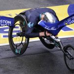 
              Marcel Hug, of Switzerland, breaks the finish line with his helmet to win the men's wheelchair division at the Boston Marathon in Boston, Monday, Oct. 11, 2021. (AP Photo/Charles Krupa)
            