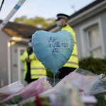 
              A balloon and floral tributes are placed on the road leading to the Belfairs Methodist Church in Eastwood Road North, in Leigh-on-Sea, Essex, England, Saturday, Oct. 16, 2021. David Amess, a long-serving member of Parliament was stabbed to death during a meeting with constituents at a church in Leigh-on-Sea on Friday, in what police said was a terrorist incident. A 25-year-old man was arrested in connection with the attack, which united Britain's fractious politicians in shock and sorrow. (AP Photo/Alberto Pezzali)
            