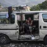 
              A man rests in an abandoned truck during the general strike in Port-au-Prince, Haiti, Monday, Oct. 18, 2021. Workers angry about the nation's lack of security went on strike in protest two days after 17 members of a US-based missionary group were abducted by a violent gang. (AP Photo/Matias Delacroix)
            