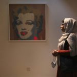 
              Fatemeh Rezaei, a retired teacher, stands next to Marilyn Monroe portrait by American artist Andy Warhol at Tehran Museum of Contemporary Art in Tehran, Iran on Oct. 19, 2021. Iranians are flocking to Tehran's contemporary art museum to marvel at American pop artist Andy Warhol’s iconic work. (AP Photo/Vahid Salemi)
            