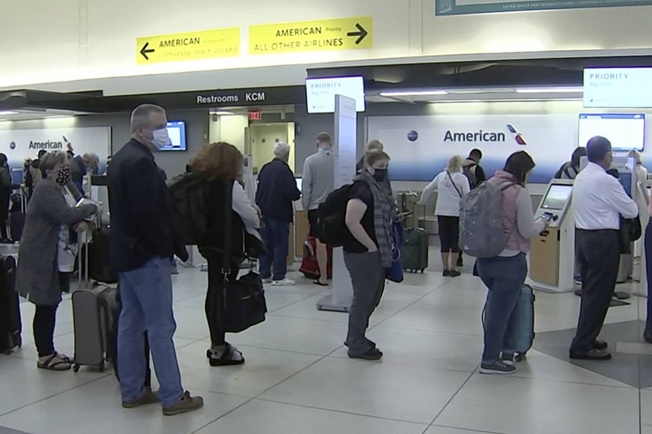 People wait in line at an American Airlines counter at an airport in Charlotte, N.C. on Sunday, Oct...