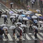 
              Commuters with umbrellas walk a crosswalk as Typhoon Mindulle travels off the coast of Japan Friday, Oct. 1, 2021, in Tokyo. Japan fully came out of a coronavirus state of emergency for the first time in more than six months as the country starts to gradually ease virus measures to help rejuvenate the pandemic-hit economy as the infections slowed. (AP Photo/Kiichiro Sato)
            