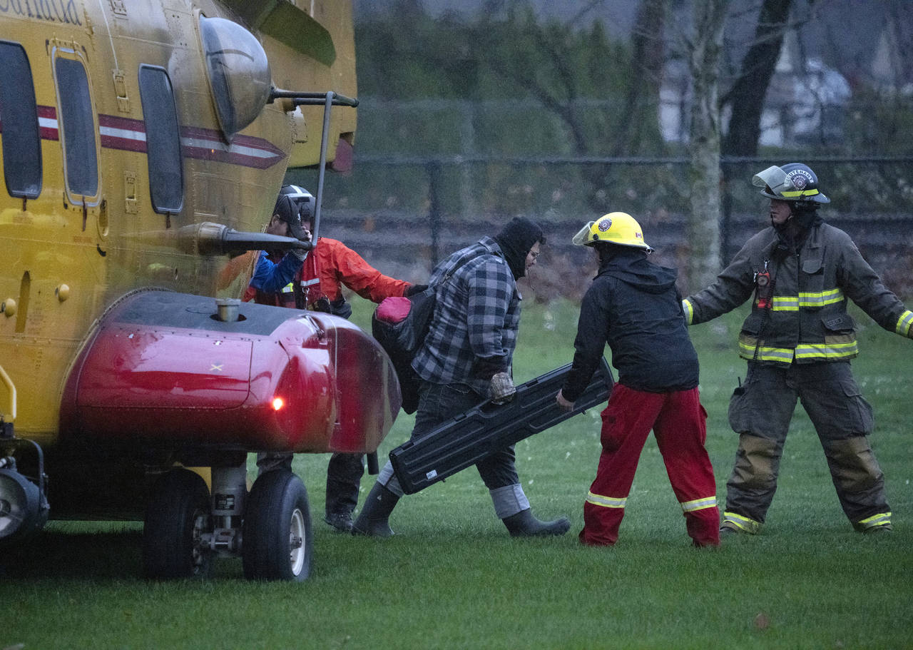 Search and rescue personnel help flood evacuees disembark from a helicopter in Agassiz, British Col...
