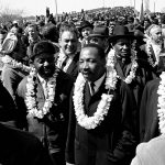 
              FILE - Martin Luther King, Jr. crosses the Edmund Pettus Bridge in Selma, Ala., heading to the capitol in Montgomery on March 21, 1965. (AP Photo/File)
            