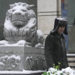 
              A security guard stands near a stone lion with a covering of snow in Beijing, China, Sunday, Nov. 7, 2021. An early-season snowstorm has blanketed much of northern China including the capital Beijing, prompting road closures and flight cancellations. (AP Photo/Ng Han Guan)
            