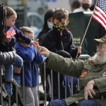 
              A disabled veteran gives a child a flower as he marches up Fifth Avenue during the 102nd annual parade Veterans Day Parade, Thursday, Nov. 11, 2021, in New York. (AP Photo/Mary Altaffer)
            