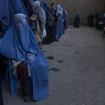 
              An Afghan woman sits on a chair as she waits with others to receive cash at a money distribution organized by the World Food Program in Kabul, Afghanistan, Saturday, Nov. 20, 2021. With the U.N. warning millions are in near-famine conditions, the WFP has dramatically ramped up direct aid to families. (AP Photo/Petros Giannakouris)
            
