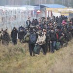 
              Migrants walk along the barbed wire as they gather at the Belarus-Poland border near Grodno, Belarus, Friday, Nov. 12, 2021. About 15,000 Polish troops have joined riot police and guards at the border. The Belarusian Defense Ministry accused Poland of an “unprecedented” military buildup there, saying that migration control didn't warrant such a force. (Leonid Shcheglov/BelTA pool photo via AP)
            