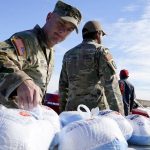 U.S. Army Sgt. 1st Class Evan Wood, left, and Staff Sgt. Javier Hernandez, right, hand out turkeys during a drive-thru turkey giveaway at the Travis L. Williams American Legion Hall Post 65 Monday, Nov. 22, 2021, in Phoenix. (AP Photo/Ross D. Franklin)