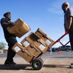 Jarvis Reddick, left, Travis L. Williams American Legion Post 65 Commander, loads cases of turkeys onto a hand truck held by Heath McCarter, of the Herozona Foundation, during a drive-thru turkey giveaway at the American Legion Hall Post 65 Monday, Nov. 22, 2021, in Phoenix. (AP Photo/Ross D. Franklin)