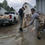 
              Tw men place sandbags to try and stop the rising floodwaters following heavy rain in Barrowtown near Abbotsford, British Columbia, Friday, Nov. 19, 2021. (Jonathan Hayward/The Canadian Press via AP)
            