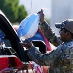 U.S. Army Staff Sgt. Javier Hernandez hands out a turkey during a drive-thru turkey giveaway at the Travis L. Williams American Legion Hall Post 65 Monday, Nov. 22, 2021, in Phoenix. (AP Photo/Ross D. Franklin)