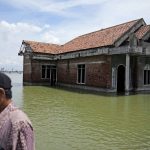 
              A man walks past a house abandoned after it was inundated by water due to the rising sea level in Sidogemah, Central Java, Indonesia, Monday, Nov. 8, 2021. World leaders are gathered in Scotland at a United Nations climate summit, known as COP26, to push nations to ratchet up their efforts to curb climate change. Experts say the amount of energy unleashed by planetary warming would melt much of the planet's ice, raise global sea levels and greatly increase the likelihood and extreme weather events. (AP Photo/Dita Alangkara)
            