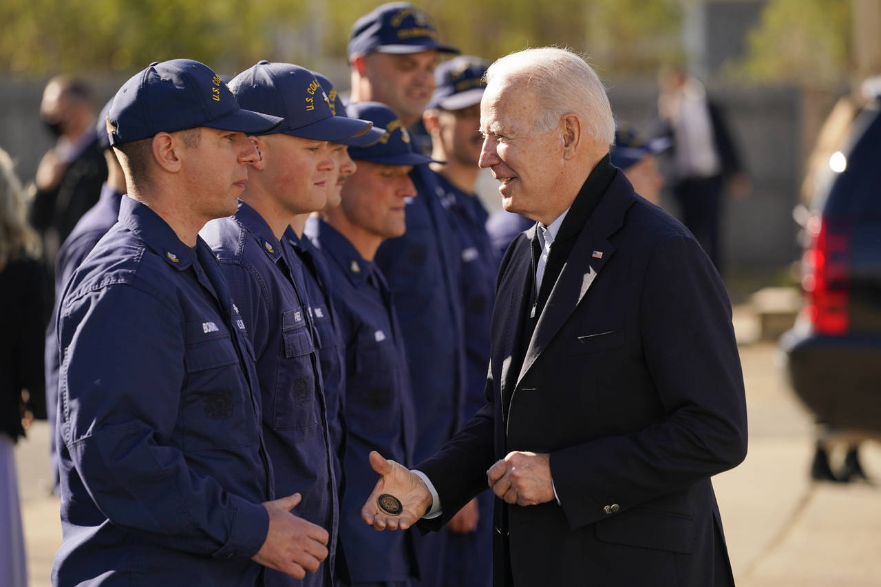 President Joe Biden hands out a challenge coin as he speaks with members of the coast guard at the ...