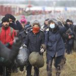 
              Migrants walk along the barbed wire as they gather at the Belarus-Poland border near Grodno, Belarus, Friday, Nov. 12, 2021. About 15,000 Polish troops have joined riot police and guards at the border. The Belarusian Defense Ministry accused Poland of an “unprecedented” military buildup there, saying that migration control didn't warrant such a force. (Leonid Shcheglov/BelTA pool photo via AP)
            