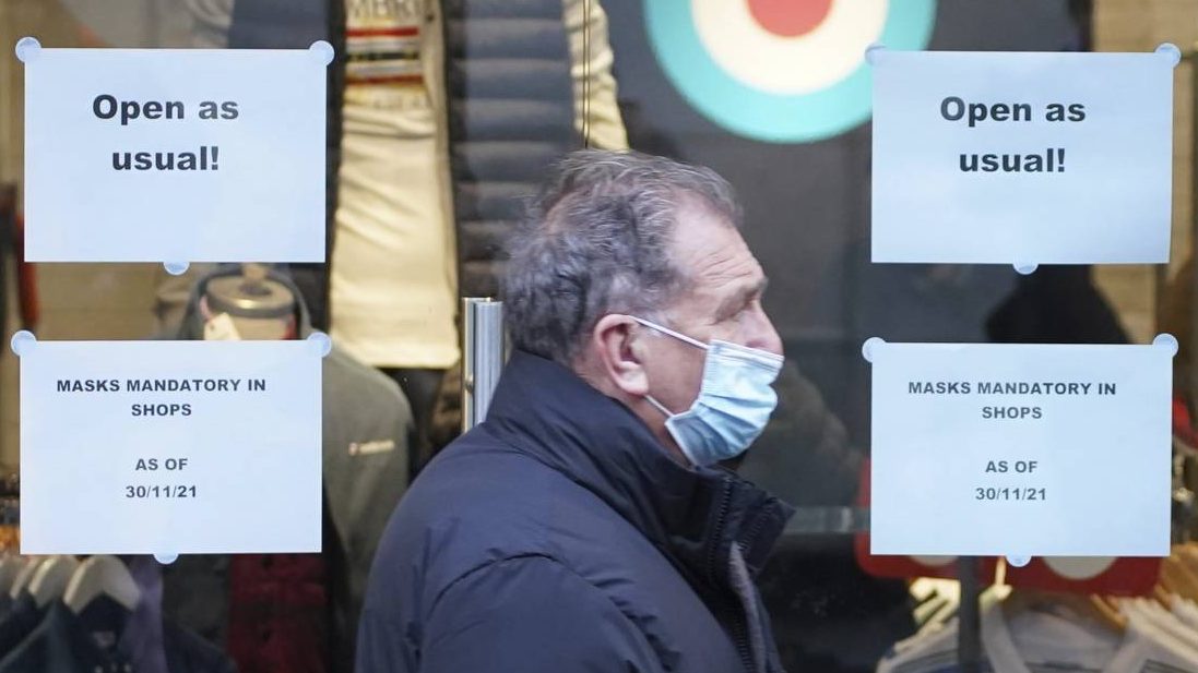 A man wears a face mask to curb the spread of COVID-19, now mandatory in Britain in shops, shopping...