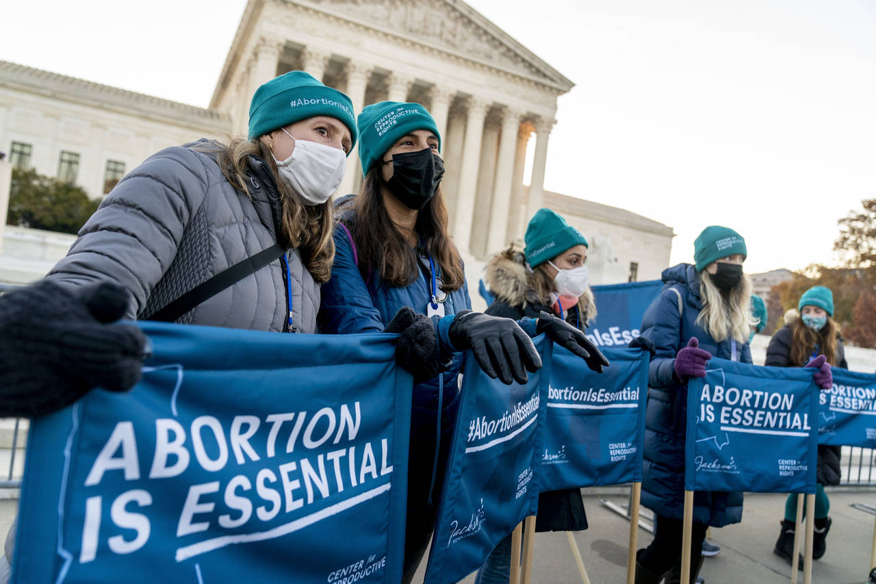 Abortion rights advocates hold signs that read "Abortion is Essential" as they demonstrate in front...