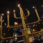 
              Rabbanit Dasi Fruchter, of the South Philadelphia Shtiebel, lights a menorah during a public Hanukkah celebration and menorah lighting ceremony in South Philadelphia on Sunday, Dec. 5, 2021. Fruchter attended and was ordained at Yeshivat Maharat in the Bronx borough of New York City, and is one of about a half-dozen ordained women who serve Modern Orthodox synagogues across the U.S. (AP Photo/Ryan Collerd)
            