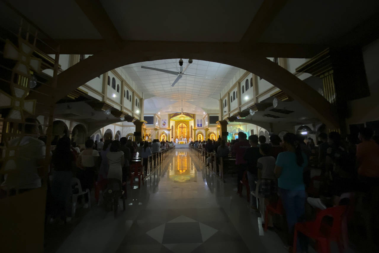 FILE - Residents attend a dimly-lit Christmas eve mass at the damaged San Nicolas de Tolentino Cath...