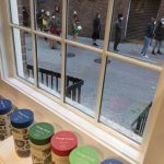 FILE - People line up outside a COVID-19 walk-in testing site as seen through a shop window, Sunday, Dec. 5, 2021, in Cambridge, Mass. Even as the U.S. reaches a COVID-19 milestone of roughly 200 million fully-vaccinated people, infections and hospitalizations are spiking, including in highly-vaccinated pockets of the country like New England. (AP Photo/Michael Dwyer, File)