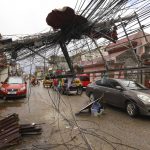 
              Cars pass by a toppled electrical post due to Typhoon Rai in Surigao city, Surigao del Norte, southern Philippines as power supply remain down on Sunday Dec. 19, 2021. The death toll in the strongest typhoon to batter the Philippines this year continues to rise and the governor of an island province especially hard-hit by Typhoon Rai said there may be even greater devastation that has yet to be reported. (AP Photo/Jilson Tiu)
            