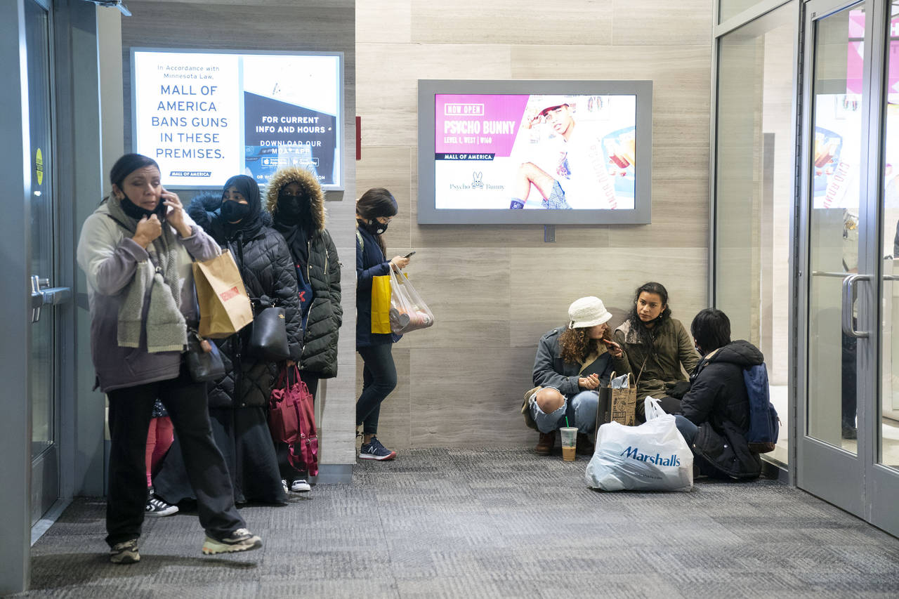 People wait near an exit to be picked up from the Mall of America following a shooting, Friday, Dec...