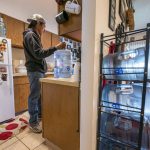 Donated five gallon water jugs, used for drinking and cooking, are seen in the home of Erland Suppah Jr., on Tuesday, Dec. 7, 2021, in Warm Springs, Ore. The massive infrastructure bill signed earlier this year promises to bring change to some Native American tribes that lack clean water or indoor plumbing through the largest single infusion of money into Indian Country. (AP Photo/Nathan Howard)