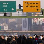 
              A man with stands on traffic sign over the highway during protest in Belgrade, Serbia, Saturday, Dec. 4, 2021. Protesters blocked roads and bridges across Serbia to protest against new the amendments to the Law on Referendum and Expropriation. (AP Photo/Darko Vojinovic)
            