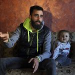 
              Ziad Khaled Hilweh, 23, who tried to migrate to Europe with his family, speaks during an interview as his daughter Jana 2 year-old sits next to him, at his parents house in the northern city of Tripoli, Lebanon, Monday, Dec. 6, 2021. Lebanese are setting off from the port city of Tripoli to attempt the perilous journey by boat to Cyprus and beyond in the hopes of reaching Europe. They are joining Iraqis, Afghans and Sudanese in leaving their homeland after Lebanon's economic collapse has thrown two-thirds of the population into poverty in just over a year. (AP Photo/Bilal Hussein)
            