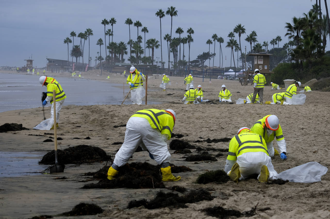 FILE - Workers in protective suits clean the contaminated beach in Corona Del Mar after an oil spil...