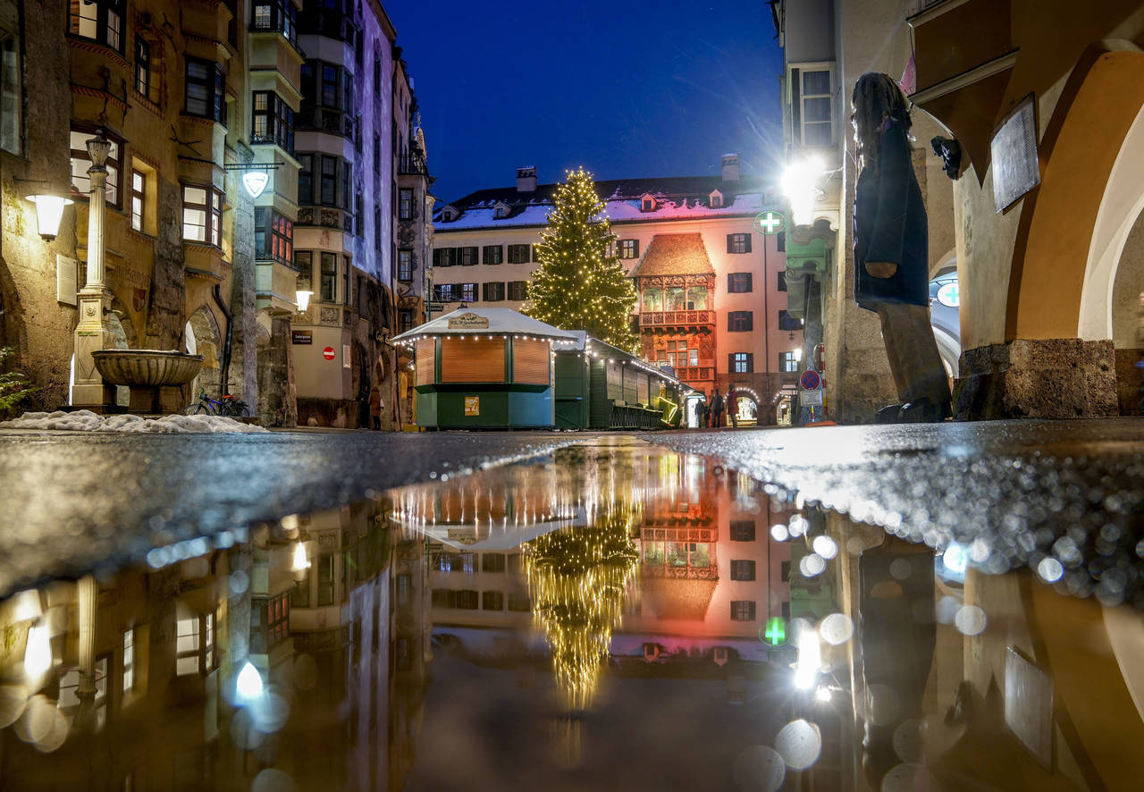FILE - The Christmas tree of the closed Christmas market is reflected in a puddle in Innsbruck, Aus...