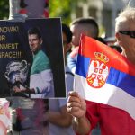 
              FILE - Supporters of Serbia's Novak Djokovic wait outside the Park Hotel, used as an immigration detention hotel where Djokovic is confined in Melbourne, Australia, Sunday, Jan. 9, 2022. The coronavirus variant has swept across Australia despite its high vaccination rate and strict border policies that kept the country largely sealed off from the world for almost two years. (AP Photo/Mark Baker, File)
            