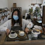 
              A barista prepares coffee at a cafe dubbed the "Winter Olympic Home" in Houheilong Miao, a village in Yanqing on the outskirts of Beijing, China, Wednesday, Jan. 5, 2022. The village has a view of the Olympics skiing venue in the distance. Its 20 mostly vacant traditional courtyard houses have been turned into lodgings and a cafe dubbed the "Winter Olympic Home." (AP Photo/Ng Han Guan)
            