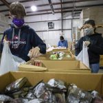 
              Volunteers Harris Springsteen, left, and Ana Willis, right, fill bags with food items for the backpack program at Feeding America food bank in Elizabethtown, Ky., Monday, Jan. 17, 2022. (AP Photo/Michael Clubb)
            