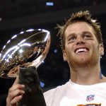 
              FILE - New England Patriots quarterback Tom Brady holds the Vince Lombardi Trophy after the Patriots beat the Carolina Panthers 32-29 in Super Bowl XXXVIII in Houston, Feb. 1, 2004. Despite reports that he is retiring, Brady has told the Tampa Bay Buccaneers he hasn't made up his mind, two people familiar with the details told The Associated Press, Saturday, Jan. 29, 2022. (AP Photo/Dave Martin, File)
            