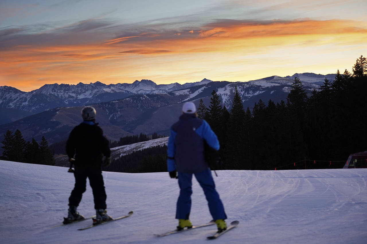 FILE - Skiers look east to the high peaks of the Rocky Mountains while skiing on man-made snow, Dec...