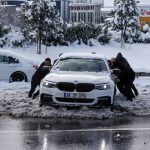 
              People push a car in a snow-covered street at Istanbul, Tuesday, Jan. 25, 2022. Rescue crews in Istanbul and Athens scrambled on Tuesday to clear throughways that came to a standstill after a massive cold front and snow storms hit much of Turkey and Greece, leaving countless people and vehicles in both cities stranded overnight in freezing conditions.(AP Photo/Emrah Gurel)
            